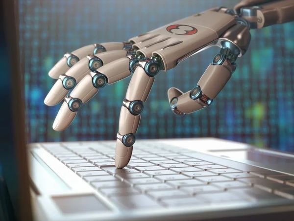 Robot hand typing on a computer keyboard.