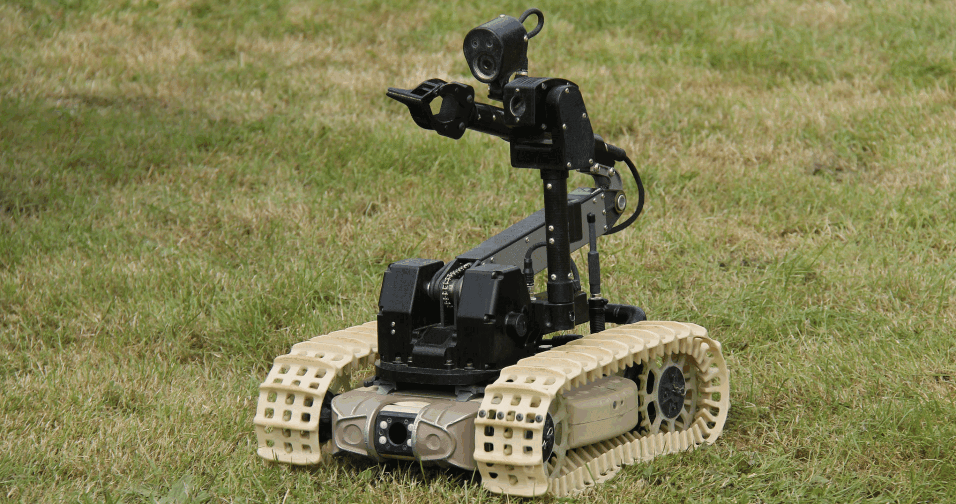 Tracked robot on grassy field.