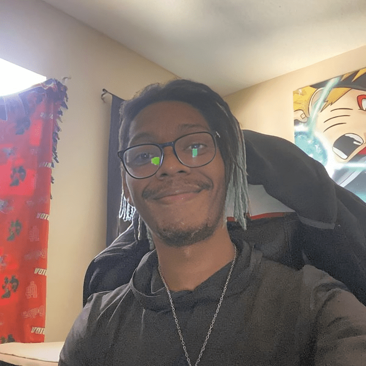 Smiling person in room with anime poster.