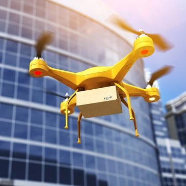 Yellow drone delivering package near building.